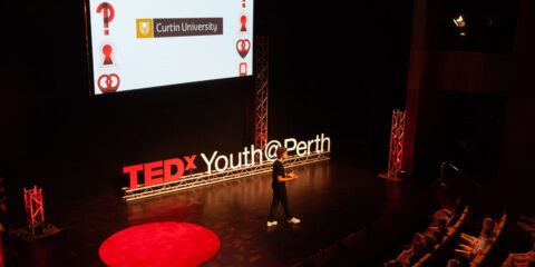 A man on stage at a ted x event