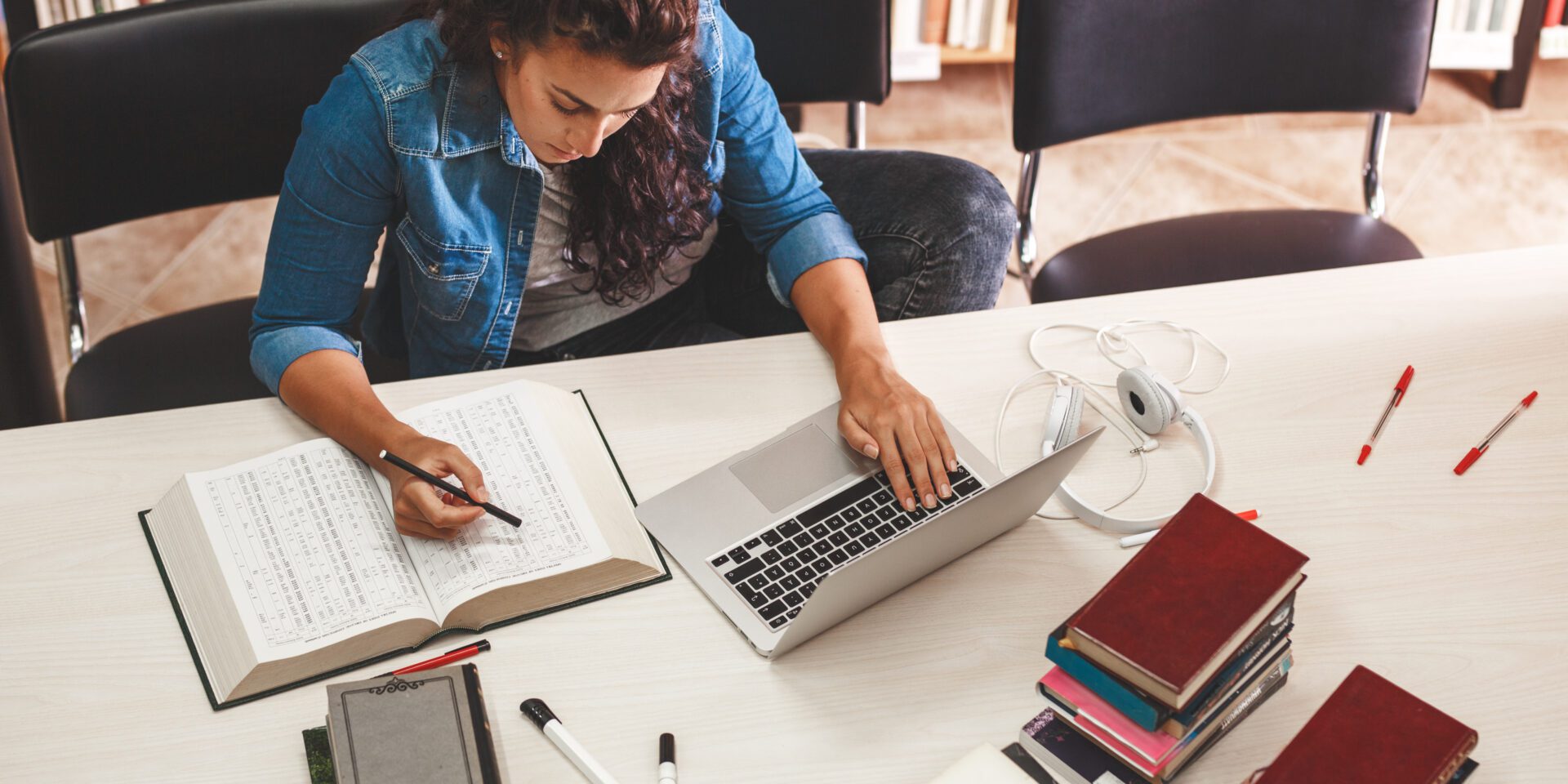 Female student in denim jacket studying in the library