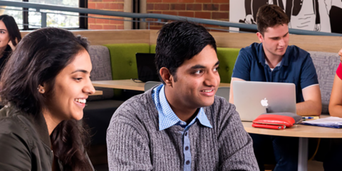 three students sitting at a desk studying