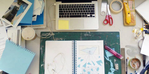 Workbook, laptop and craft materials on desk