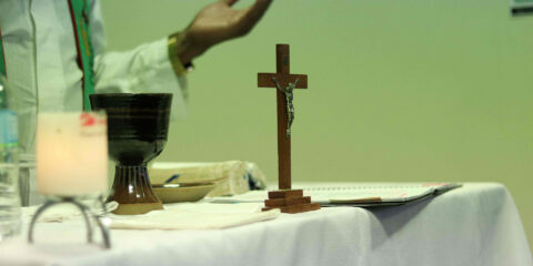 Table with a Christian cross, candle and cup.