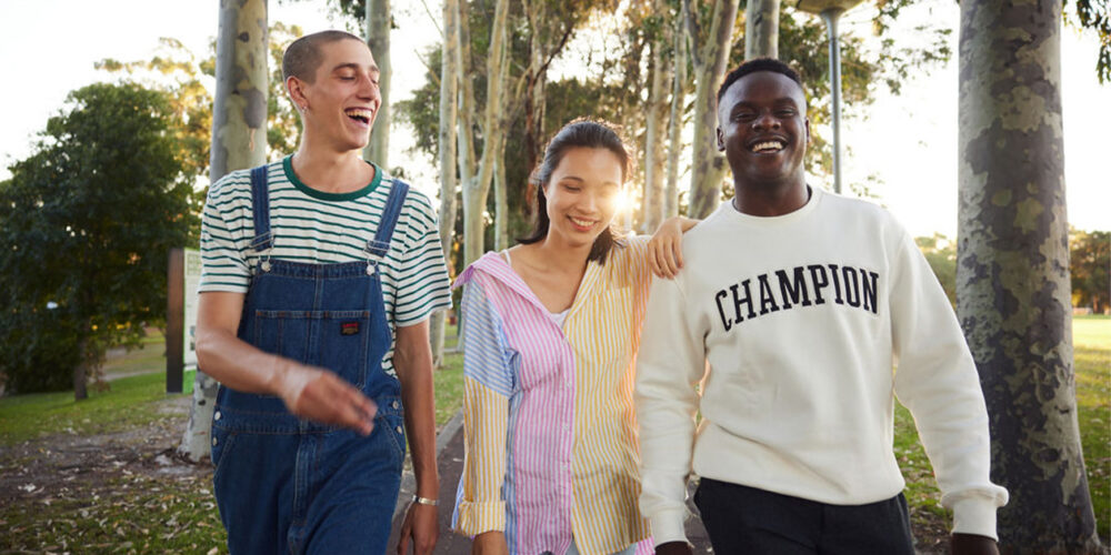 Three students smiling walking outdoors at Curtin Perth campus.
