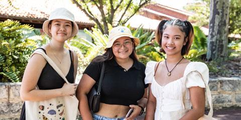 Three international students smile at the camera.