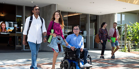 Students walk and move out of Curtin Connect. Two students walk out, one student uses a wheelchair.