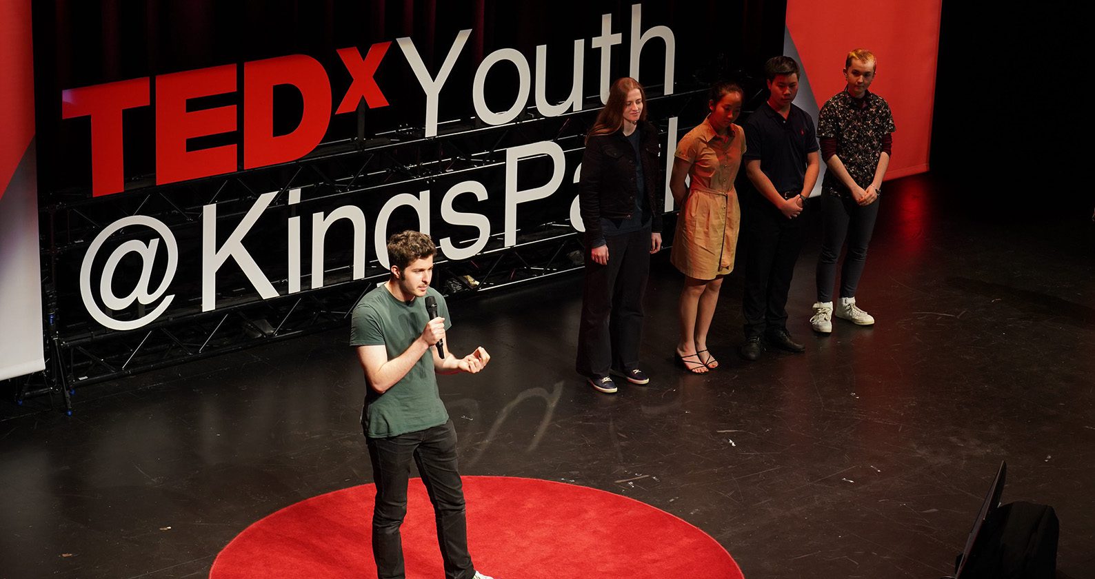 Person stands on stage talking at TEDx Youth Kinds Park