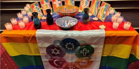 Table with rainbow flag and various religious symbols.