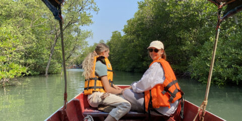 Two students sit smiling together on a boat, as part of their study abroad experience.