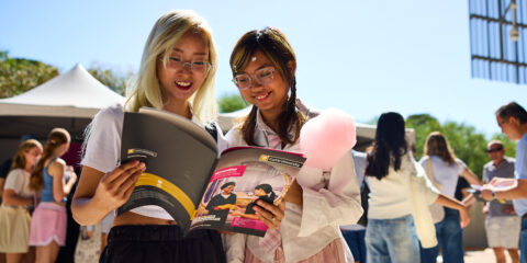 Two students read a course guide on the Curtin campus