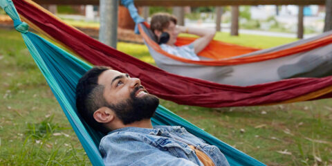 A student laying in a hammock looking up and smiling.