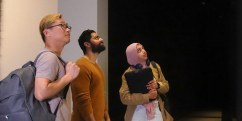 Three students gazing at an image at the Gallery.