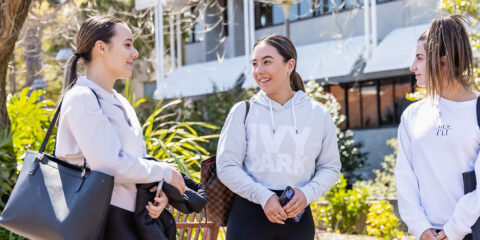 Three students standing and talking to each other.