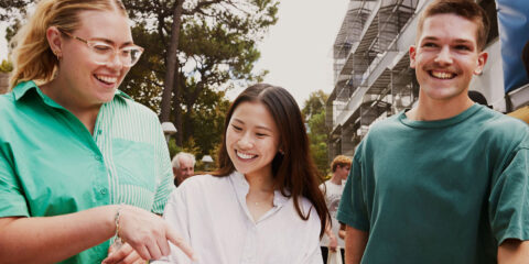 Three students looking down at a map and smiling.