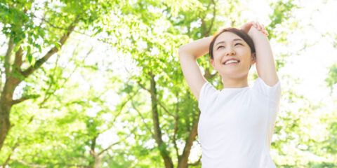 Women stretching with trees in the background.