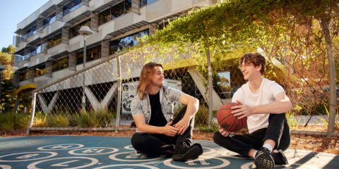 Students sitting down on campus holding a basketball