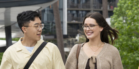 Three students laughing and walking from the bus port