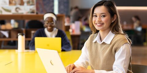 A student works on a laptop in a library