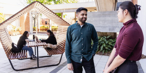 Students talking and studying outdoors on campus seating.